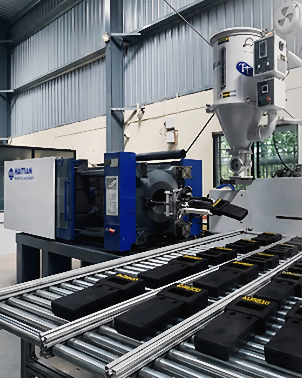 Haitian injection moulding machine with moulded parts on a roller conveyor